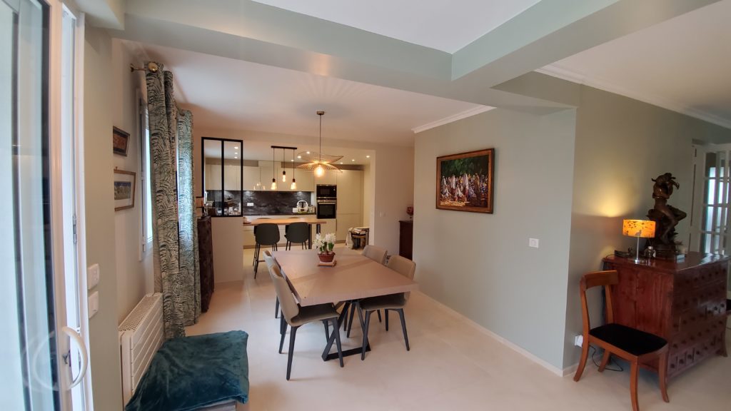 Salle à manger cosy avec table Roche Bobois, lumineuse après rénovation, mur mizzle vert gris et blanc gris cassé